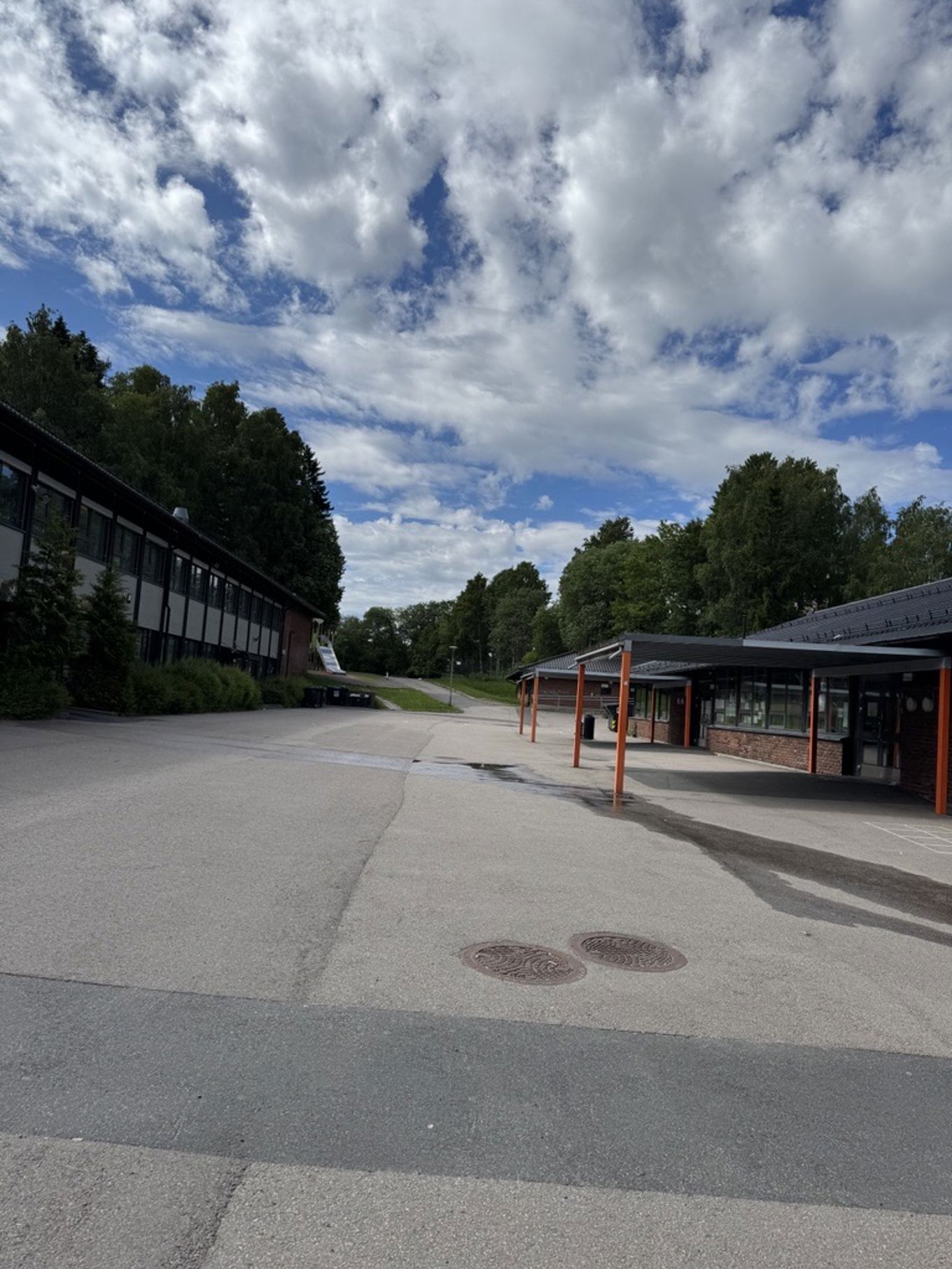 et brolagt område med bygninger og trær i bakgrunnen